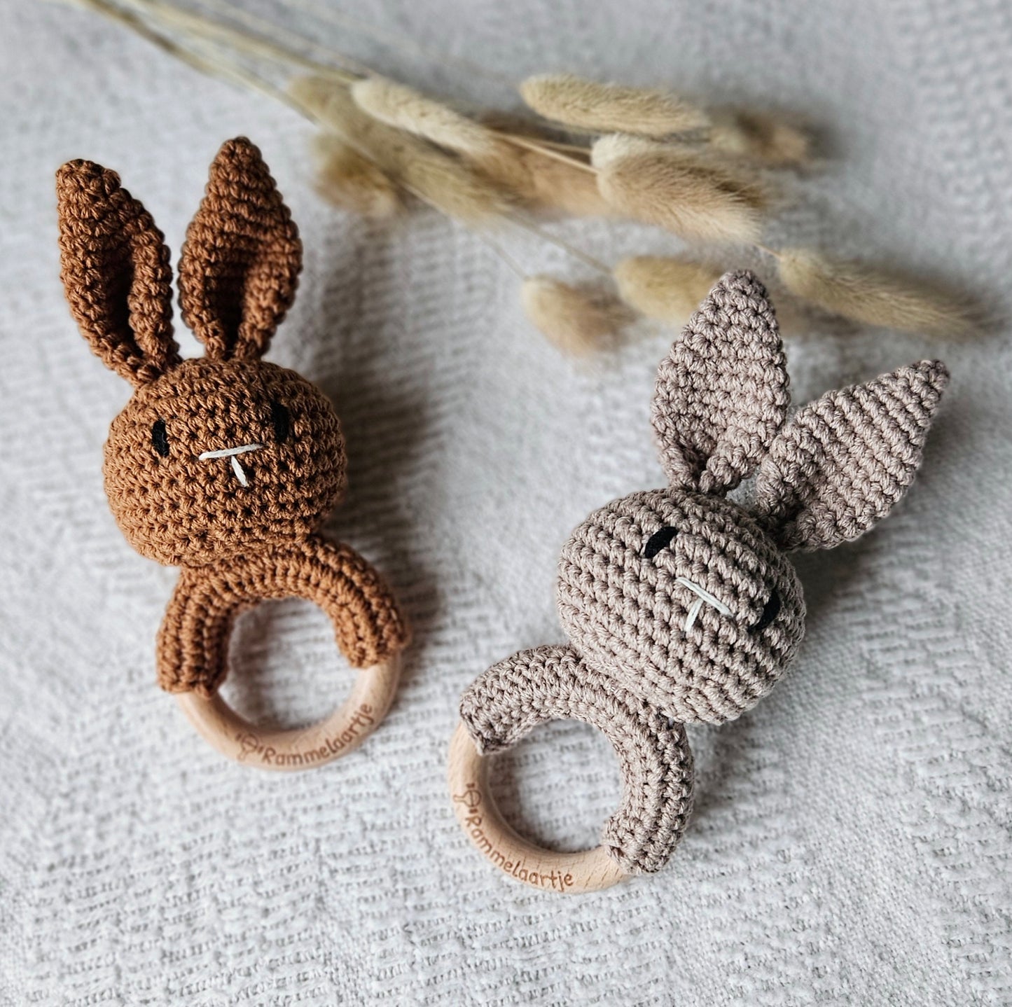 Twee handgemaakte gehaakte konijn rammelaars in de kleuren zand en bruin, met houten ring – stijlvol babyspeelgoed van Rammelaartje