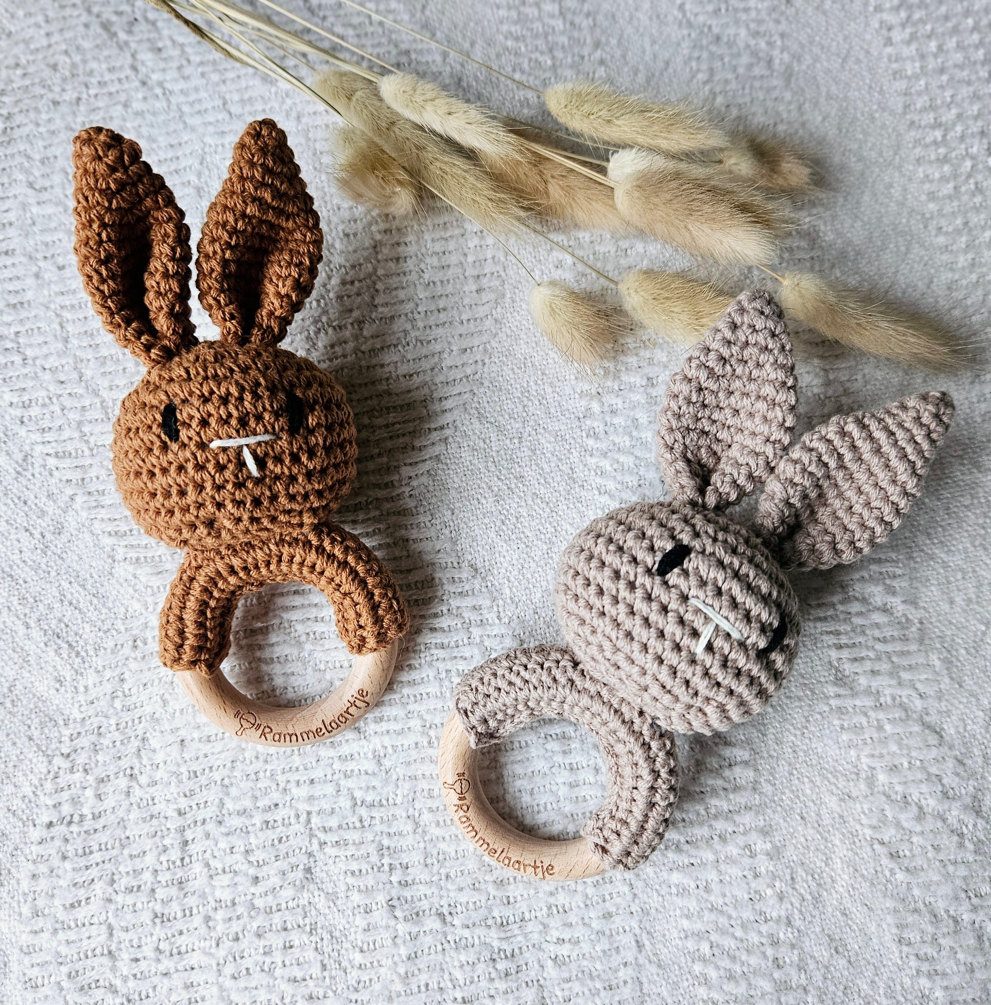 Twee handgemaakte gehaakte konijn rammelaars in de kleuren zand en bruin, met houten ring – stijlvol babyspeelgoed van Rammelaartje